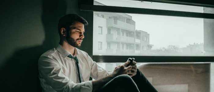 Unglücklicher Mitarbeiter schaut auf sein Handy.